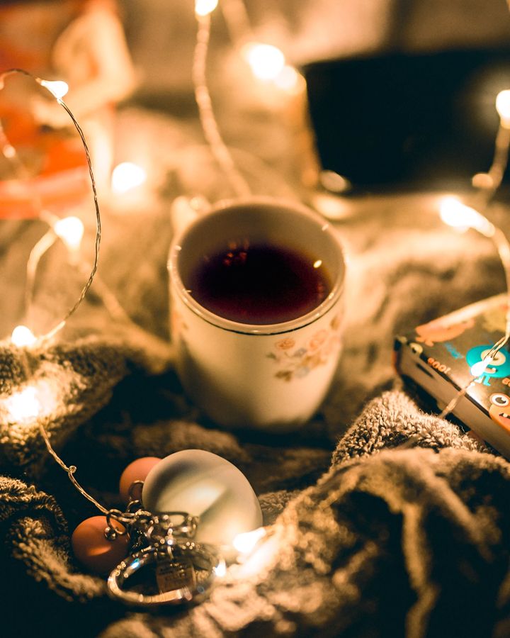 Taza de té entre luces cálidas y una manta